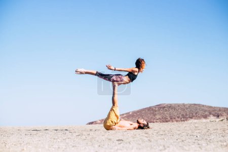 two adults together at the beach doing exercises on the sand - fitness and healthy lifestyle - doing acroyoga in silence 