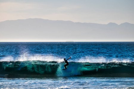 Téléchargez les photos : Adolescent surf à la vague dans la plage tenerife des Amériques combinaisons blanches et belle et parfaite vague - en image libre de droit