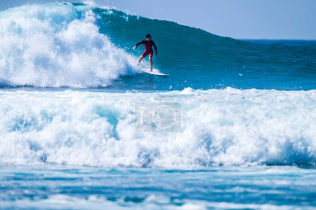 Téléchargez les photos : Un homme s'entraîne et surfe en vacances en été ou en hiver en combinaison de plongée - belle et grande vague dans l'île des Canaries - en image libre de droit