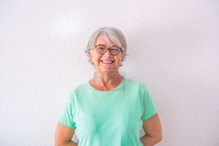 portrait of one pretty old and mature woman looking at the camera smiling and laughing - happy senior lady with a white background  