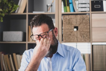 Photo for Unhealthy stressed businessman taking off eyeglasses, rubbing eyelids, suffering from dry eyes syndrome due to long computer overwork, massaging nose bridge relieving pain at office at home - Royalty Free Image