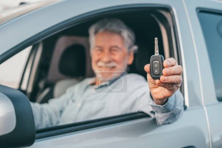 Téléchargez les photos : Portrait de vieil homme heureux montrant les clés de la voiture à la caméra. Client satisfait de profiter de sa nouvelle voiture. - en image libre de droit