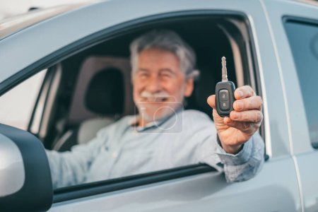 Téléchargez les photos : Portrait de vieil homme heureux montrant les clés de la voiture à la caméra. Client satisfait de profiter de sa nouvelle voiture. - en image libre de droit