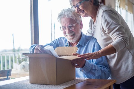Glückliche ältere ältere Familienpaare auspacken Karton Box, zufrieden mit Internet-Shop kaufen oder unerwartete Geschenk, das Gefühl der schnellen Lieferung Versandservice aufgeregt, positives Einkaufserlebnis. 