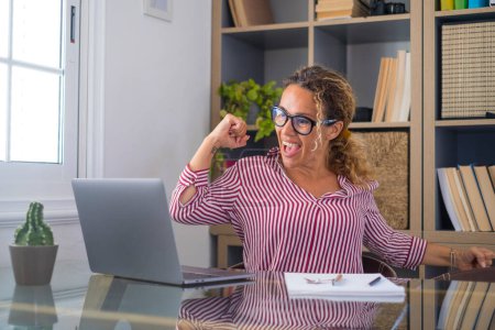 Caucasian woman office worker feeling excited raising fist celebrating career promotion or reward. Businesswoman delighted on receiving good news online using laptop at office workplace   Stickers 619931468