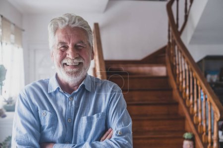 Heureux vieil homme aux cheveux gris, âgé des années 80 souriant avec des dents blanches à la maison. Portrait d'un grand-père joyeux relaxant intérieur. 