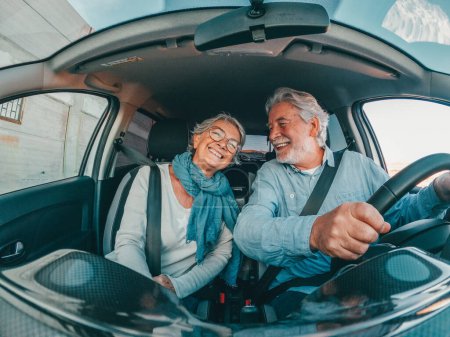 Zwei glückliche Senioren, die Spaß haben und gemeinsam mit dem Auto in den Urlaub fahren und neue Orte entdecken. 