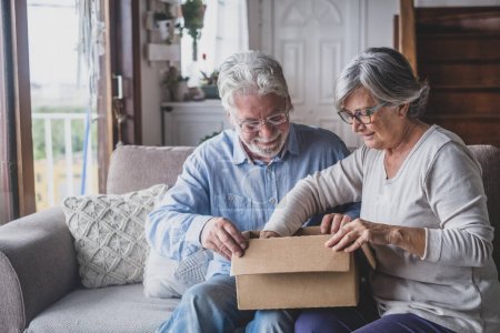 Glückliche ältere ältere Familienpaare auspacken Karton Box, zufrieden mit Internet-Shop kaufen oder unerwartete Geschenk, das Gefühl der schnellen Lieferung Versandservice aufgeregt, positives Einkaufserlebnis. 