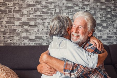 Photo for Couple of two old seniors hug together having fun and taking care each others at home on the sofa. Mature people in love enjoying life. - Royalty Free Image
