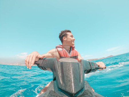 Téléchargez les photos : Homme adolescent profitant de l'été dans un jet ski au milieu de la mer s'amuser à courir seul et isolé. - en image libre de droit