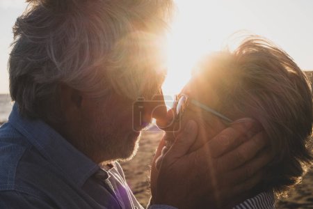retrato y primer plano de dos felices enamorados ancianos bailando sonriendo con el sol de la puesta de sol entre sus cabezas  