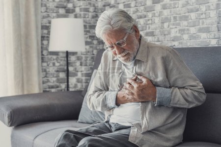 Photo for Worried elder senior man feeling bad, upset old middle aged grandfather touching chest feel sudden pain heartburn having heart attack sit on sofa at home - Royalty Free Image