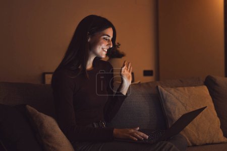 Photo for Happy caucasian young girl student watch webinar listen online course communicate by conference video call e learn language in app laugh study with teacher lesson look at laptop at night - Royalty Free Image