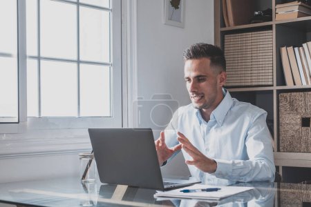 Photo for Attractive caucasian man sit at homeoffice room wearing headset take part in educational webinar using laptop. Video call event with clients or personal chat with friend remotely concept - Royalty Free Image