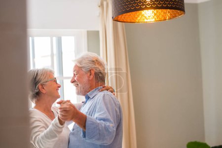 Photo for Joyful active old retired romantic couple dancing laughing in living room, happy middle aged wife and elder husband having fun at home, smiling senior family grandparents relaxing bonding together - Royalty Free Image