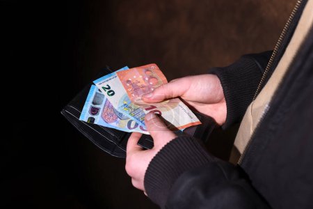 Photo for Close up of a man's hands taking money from his wallet. Illustration of rising prices and cost of living - Royalty Free Image