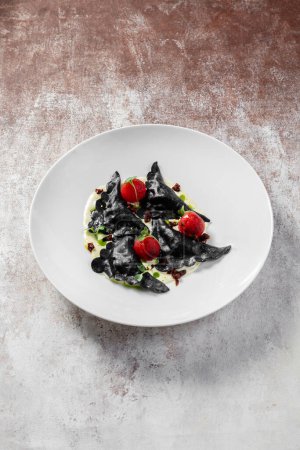 Photo for Dough dumplings with cuttlefish ink and salmon and onion filling in a creamy sauce. Vareniki are decorated with cherry tomatoes and microgreen sprouts. A dish in a light ceramic plate on a light background. - Royalty Free Image