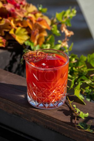 Foto de Cóctel Bloody Mary hecho de jugo de tomate, vodka y un trozo de hielo en un vaso facetado transparente. El cóctel se apoya sobre un fondo de madera. - Imagen libre de derechos