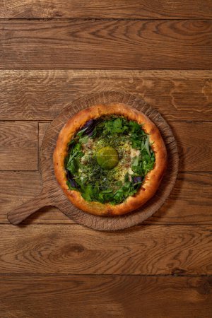Photo for Adjarian khachapuri with suluguni cheese, yolk, cilantro and herbs on a wooden stand with a handle. - Royalty Free Image