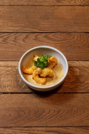 Téléchargez les photos : Crevettes tempura avec sauce au fromage, beurre et coriandre. La nourriture est dans un bol rond en céramique. - en image libre de droit