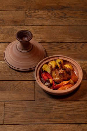 Photo for Leg of lamb baked with potatoes, paprika, carrots and red onions in a ceramic dish with a lid. - Royalty Free Image