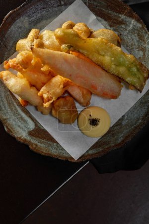 Téléchargez les photos : Paprika, oignons, carottes et crevettes frits en pâte dans de la graisse profonde sur du papier léger reposent sur une plaque en céramique. - en image libre de droit