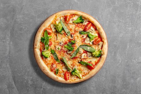 Téléchargez les photos : Pizza au levain végétarien avec légumes, champignons, feuilles de basilic, fromage parmesan et sauce tomate ; La pizza repose sur un fond de pierre grise. - en image libre de droit