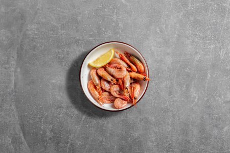 Photo for Shrimps fried in beer with a slice of lemon in a ceramic dish on a gray stone background. - Royalty Free Image