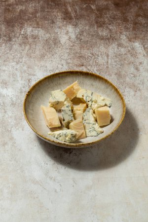 Téléchargez les photos : Parmesan ukrainien et dorblyu fromage coupé en morceaux et couché dans une assiette en céramique sur un fond de tissu léger. - en image libre de droit