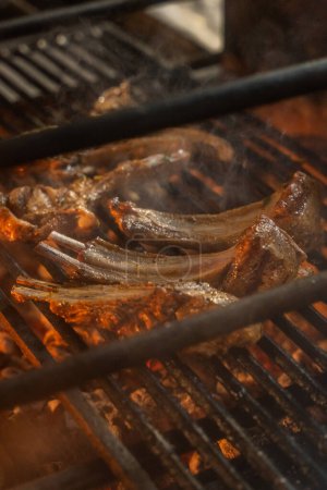 Photo for Several pieces of lamb rack lie on a metal grill grate over hot coals. - Royalty Free Image