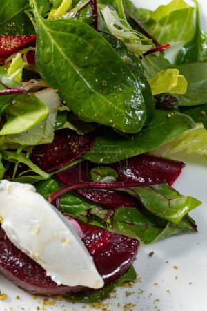 Photo for Mix salad of several types of lettuce with paprika, caramelized beets, gorgonzola and balsamic. Food lies on a light ceramic plate on a light tablecloth. - Royalty Free Image