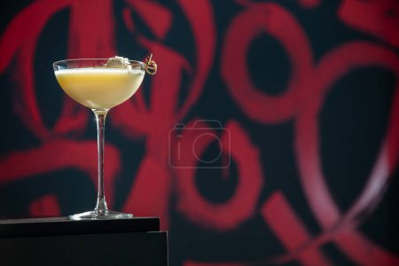 Téléchargez les photos : Un cocktail avec glace et olive panée sur une brochette dans un verre qui se dresse sur la table sur le fond d'un mur peint - en image libre de droit