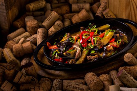 Photo for Potatoes with mussels, meat, peppers, onions, lettuce, tomatoes, arugula in a plate lying on a set of wine corks - Royalty Free Image