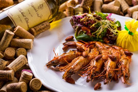 Photo for Salad with shrimps, almonds, lemon, endive, salad in a plate lying on a set of wine corks with wine stands - Royalty Free Image
