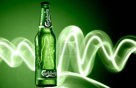 Foto de Carlsberg Botella de cerveza sobre fondo verde con rayas de luz - Imagen libre de derechos