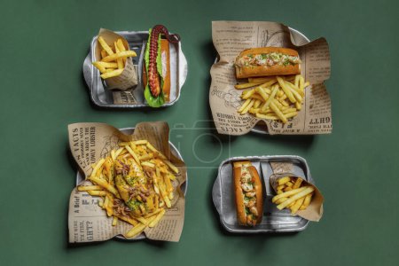 Foto de Assorted fish dogs. On a green paper background, there are four metal forms with different fish dogs. Octopus bun, shrimp bun in garlic sauce, shrimp bun in creamy sauce, salmon bun with octopus fries in cheese sauce. Next to each fish dog is a porti - Imagen libre de derechos