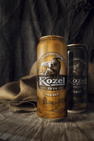 Téléchargez les photos : Velkopovicky Kozel Bière en boîtes de fer clair et sombre debout sur un support en bois rugueux sur un fond de toile de jute - en image libre de droit