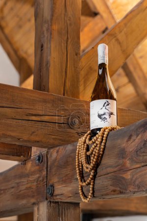 Foto de Una botella de vino seco blanco ucraniano Beykush se encuentra en vigas de madera, perlas de madera cuelgan de abajo. - Imagen libre de derechos