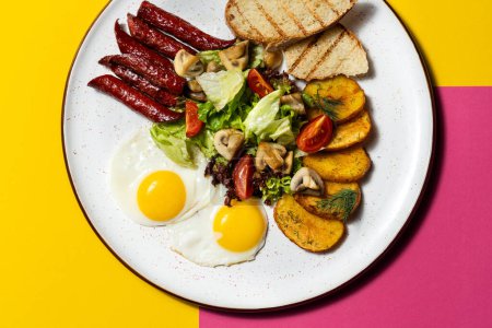 Photo for English breakfast of two fried eggs, sausages, fried potatoes, toast and salad. Food lies on a white ceramic plate on a paper colored background. - Royalty Free Image