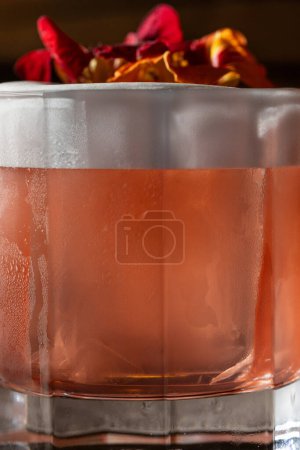 Téléchargez les photos : Cocktail avec whisky, extrait de citron, liqueur de marasquin et décoré de fleurs sur le dessus. Un cocktail dans un verre à l'ancienne est placé sur une surface en cuir. - en image libre de droit