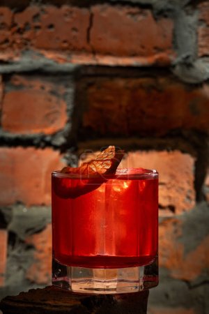 Téléchargez les photos : Cocktail avec apéro et bourbon, vermouth et jus de citron avec sirop de sucre. Un cocktail dans un verre à l'ancienne est debout sur une surface en brique. - en image libre de droit