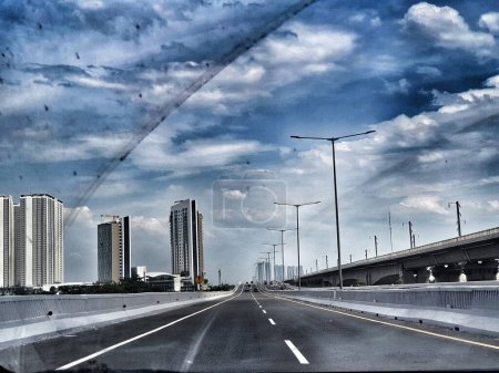Téléchargez les photos : Jakarta, Indonésie en juillet 2022. L'atmosphère et le paysage lors de la conduite sur le Jakarta Cikampek Elevated Toll Road, ou maintenant connu sous le nom Mohammad Bin Zayed Toll Road (MBZ). Entouré de grands bâtiments et beau ciel bleu et nuages blancs. - en image libre de droit