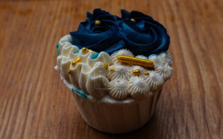 Téléchargez les photos : Luxurious and elegant cupcakes, with white cream and navy blue with gold sprinkles. It has a sweet and creamy taste. - en image libre de droit