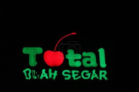 Téléchargez les photos : Bekasi, Indonesia in July 2022. The TOTAL Buah Segar logo shining brightly at night against the dark night sky. Total fresh fruit is a big fruit shop that is famous in Indonesia because it provides many types of fruit. - en image libre de droit