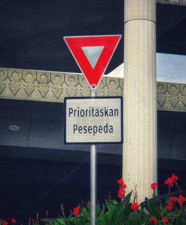 Foto de Cyclists Priority signs posted on one of the streets in the city of Jakarta. The sign is made of steel, with a red outer triangle and a white inner triangle. Below it is written Prioritize cyclists. - Imagen libre de derechos