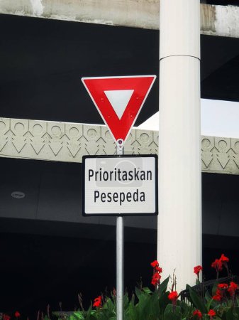 Foto de Cyclists Priority signs posted on one of the streets in the city of Jakarta. The sign is made of steel, with a red outer triangle and a white inner triangle. Below it is written Prioritize cyclists. - Imagen libre de derechos