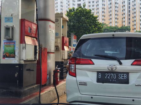 Foto de Jakarta, Indonesia in July 2022. A female gas station attendant refuels a white car. This gas station is owned by Pertamina. - Imagen libre de derechos