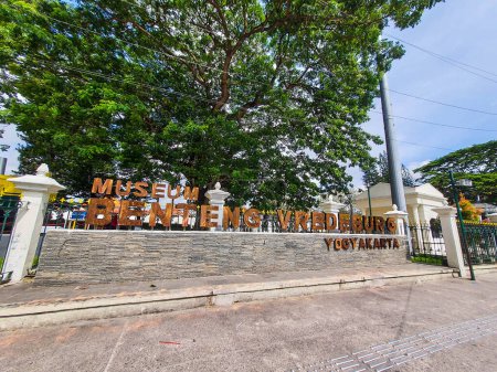 Téléchargez les photos : Yogyakarta, Indonésie en novembre 2022. Il est dit Musée Fort Vredeburg en brun, vous pouvez voir plusieurs visiteurs passant devant elle. Il s'agit d'un musée situé devant le bâtiment Agung et le palais du sultan. - en image libre de droit