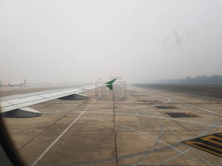 Téléchargez les photos : Riau, Indonésie en octobre 2019. Photo de la fenêtre de l'avion lors de l'atterrissage, où les conditions météorologiques étaient brumeuses en raison des effets des incendies de forêt. Il peut être vu de la fenêtre de l'avion lion à côté de l'avion que vous voyagez sur. - en image libre de droit