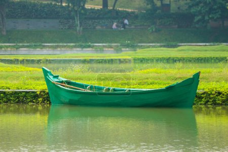 Téléchargez les photos : Un bateau vert sans passagers était stationné sur le bord du lac. Ce bateau vert est utilisé pour l'entretien du parc au milieu du lac. Un jardin en forme de carte de L'Indonésie à Taman Mini Indonésie Indah. - en image libre de droit